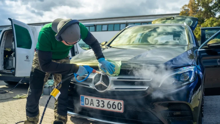 Steamer renser fronten på en mørkeblå Mercedes med damp